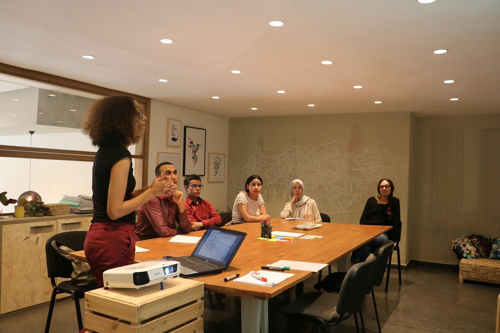 A small group listening to a coach at a workshop table